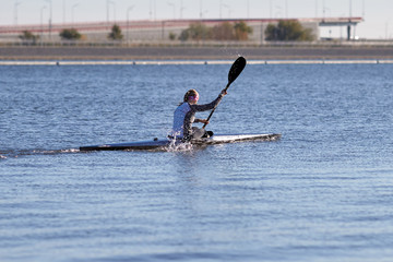 Girl athlete engaged in canoeing on a water channel.