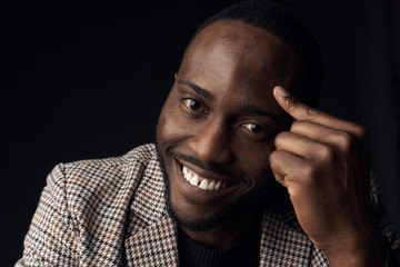 Dark key portrait of smiling man with dark eyes, weared in plaid suit jacket. Studio shot