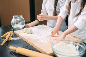 Obraz na płótnie Canvas funny girls kids are preparing the dough in the kitchen.