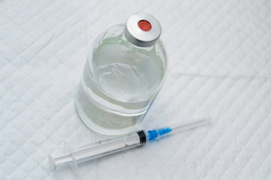 .vial with clear drug solution and a syringe