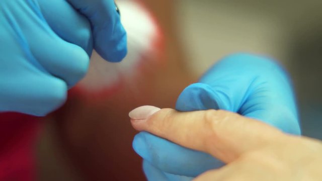 Manicure treatment in a beauty parlor.  Qualified manicurist buffering and brushing client&rsquo;s nail then clipping hangnails with cuticle nippers. Close up