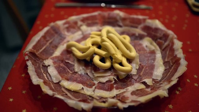4K, Close up of slice spanih ham called Jamon Serrano from plate of tasty Tapa. Iberian cured ham dish on the table of chrismast holiday, traditional spanish food-Dan