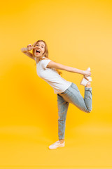 Full length, positive girl, shows a peaceful gesture, two fingers, on a yellow background