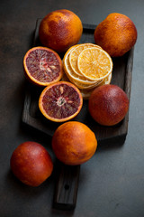 Wooden serving tray with sicilian blood oranges and orange fruit chips, vertical shot