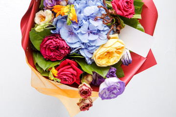 Image from above bouquet of multi-colored roses with card on white background