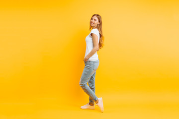 Fototapeta na wymiar Full length portrait of a cheerful beautiful girl, posing on a yellow background
