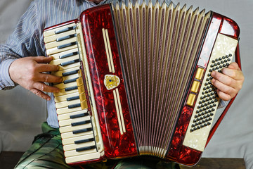 An old accordion is fun to play in the hands of an elderly musician. This musical instrument will cheer people for a long time