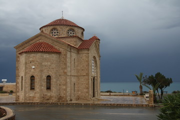 A view of the sea and church before the storm with dark blue clouds approaching the island