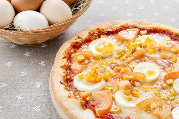 Easter pizza with eggs, cheese, corn and tomato sauce.