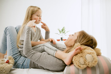 Young mother and her little daughter at home at sunny morning. Soft pastel colors. Happy family...