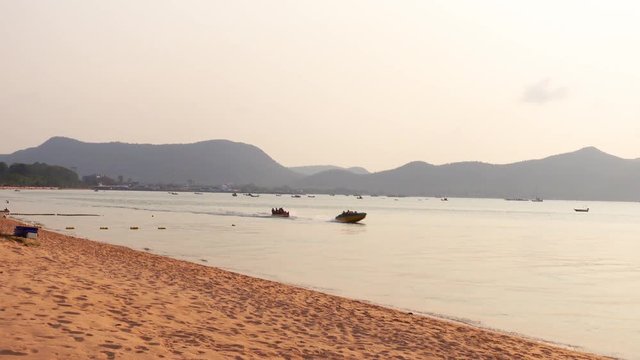 View of the Pattaya Beach with the speed boat running in the sea in the evening in Thailand