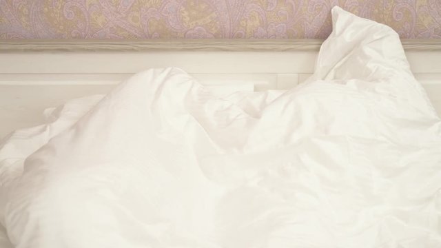 Two little girls in pajamas hiding under a blanket and then peeking out of it and laughing