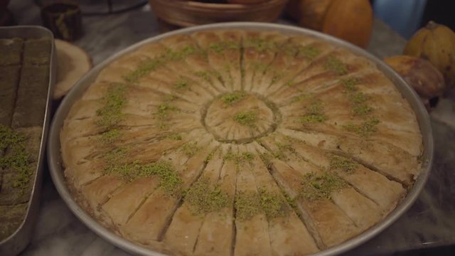 Close up view of tasty cooked sweet kunafa sprinkled with pistachios lying on the table in the kitchen. Food preparation concept