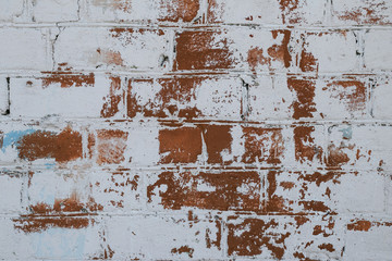 Brick wall texture in old white paint closeup. Wall of red brick painted white peeling paint. Space texture. Old grunge wall background.