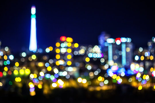 Night bokeh city light with illuminated TV tower, abstract blur defocused background