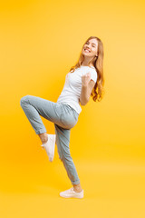 Full length, enthusiastic girl , celebrating success on a yellow background