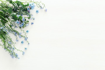 spring bouquet of blue and delicate blue flowers over white wooden background. top view, flat lay