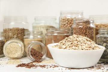Many jars with grains, seeds, legumes, flours and various food ingredients. Healthy food concept.