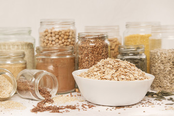 Many jars with grains, seeds, legumes, flours and various food ingredients. Healthy food concept.