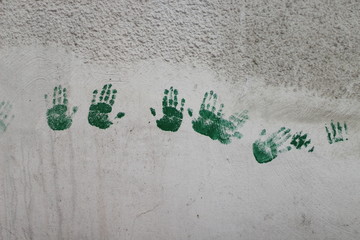 Green handprints on the white wall