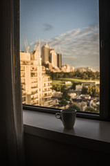 Fototapeta na wymiar Kaffeetasse auf Fensterbank vor Skyline von Sydney