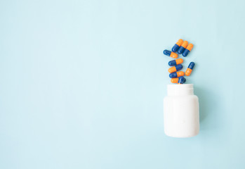 Pills spilling out of pill bottle and isolated on blue. Top view with copy space. Medicine concept