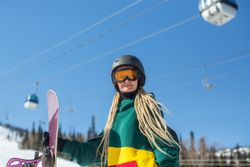 Portrait of female snowboarder standing outdoors holding a snowboard.