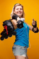 Happy athletic blonde girl with roller skates on shoulder in studio .