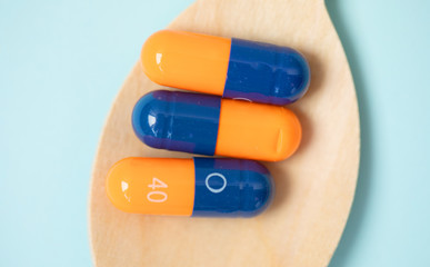 medicine tablets on a wooden spoon isolate on blue background.