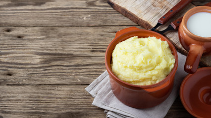 Mashed potatoes in a clay pot, vintage wood background, rustic style.