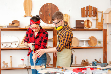 A man and a woman work together and have a good time in the carpentry shop. The concept of teamwork and manual labor