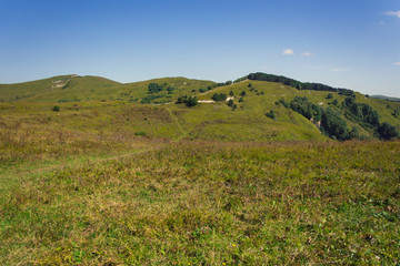 Naklejka premium A large panorama of the hilly and mountainous area on a summer day.