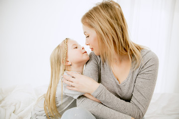 Young mother and her little daughter at home at sunny morning. Soft pastel colors. Happy family...