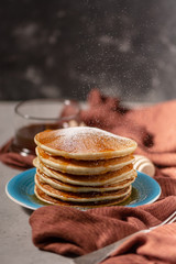 Pancake folded stack of with liquid honey and sugar powder on stone background