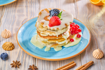 Stack of homemade pancakes with strawberrie, banana and red currant on a blue plate