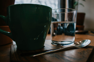 Cup of coffee on a wooden table with glass of water. Coffee shop in local area. Cozy retro style.