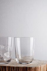 Ice cube in a glass on a wood table.