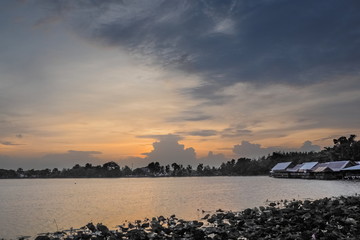 Naklejka premium Lake view evening of many clouds moving in the sky with colorful red sun light in the sky background, sunset at Krajub reservoir, Banpong, Ratchaburi, Thailand.