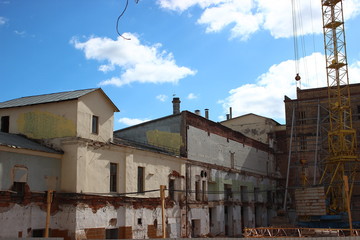 the destruction of the old building, reconstruction, structural changes. construction, high-rise crane works on the site. the building is made of brick, tiles on the walls. 