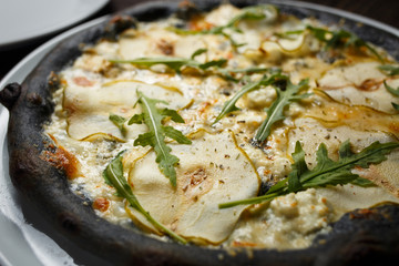 Black cheese pizza served on table in restaurant