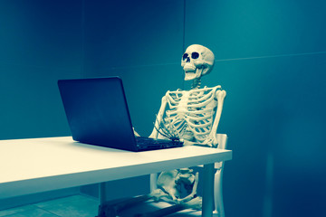 esqueleto en oficina trabajando y muerto de aburrimiento