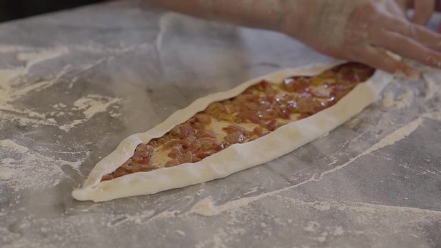 Chef hands making turkish food fatayer in modern restaurant kitchen close up. Dough with roasted meat with vegetables are ready for baking. Turkish food preparation