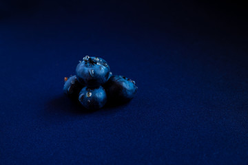 juicy summer berry is blueberries with drops of honey on a blue background