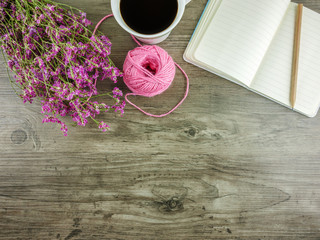 Flat lay,top view grey wooden desk with stationery including notebook and pencil with a cup of coffee,flowers  and copy space 