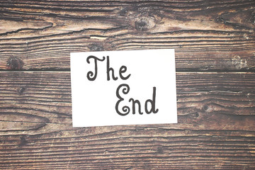 The end sign on paper on wooden table