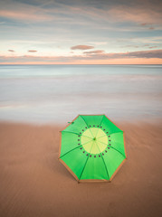 umbrella on the sand of the beach in a sunset in long exposure