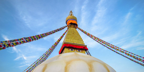 Top of Boudhanath stupa, eyes watching, prayer flags, blue sky, Kathmandu, Nepal