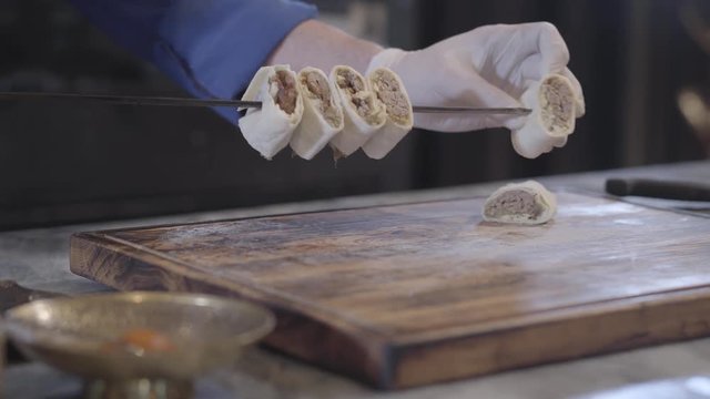 Cook stringing kebab pieces wrapped in pita lavash on the skewer close up. Successful man cooking lula kebab in modern turkish restaurant. Cook