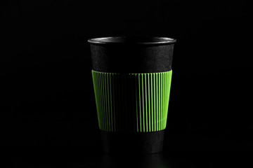 a glass of hot tea or coffee. Black paper glass with a lid on a black background. side view