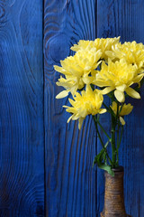 Bouquet of yellow chrysanthemum flowers against the blue wooden background
